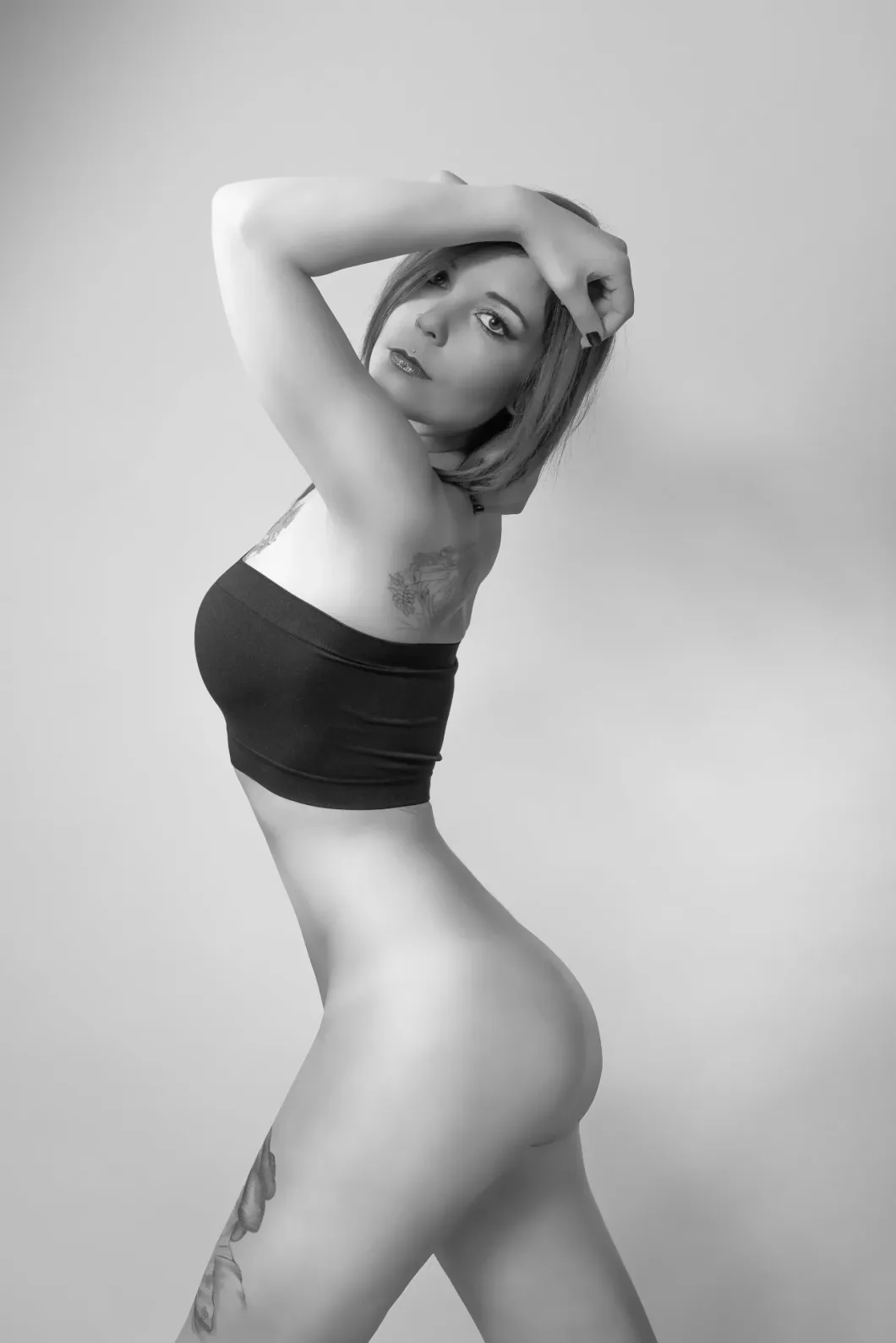 Frau in Unterwäsche in Schwarzweiß-Pose, zeigt Tattoos.