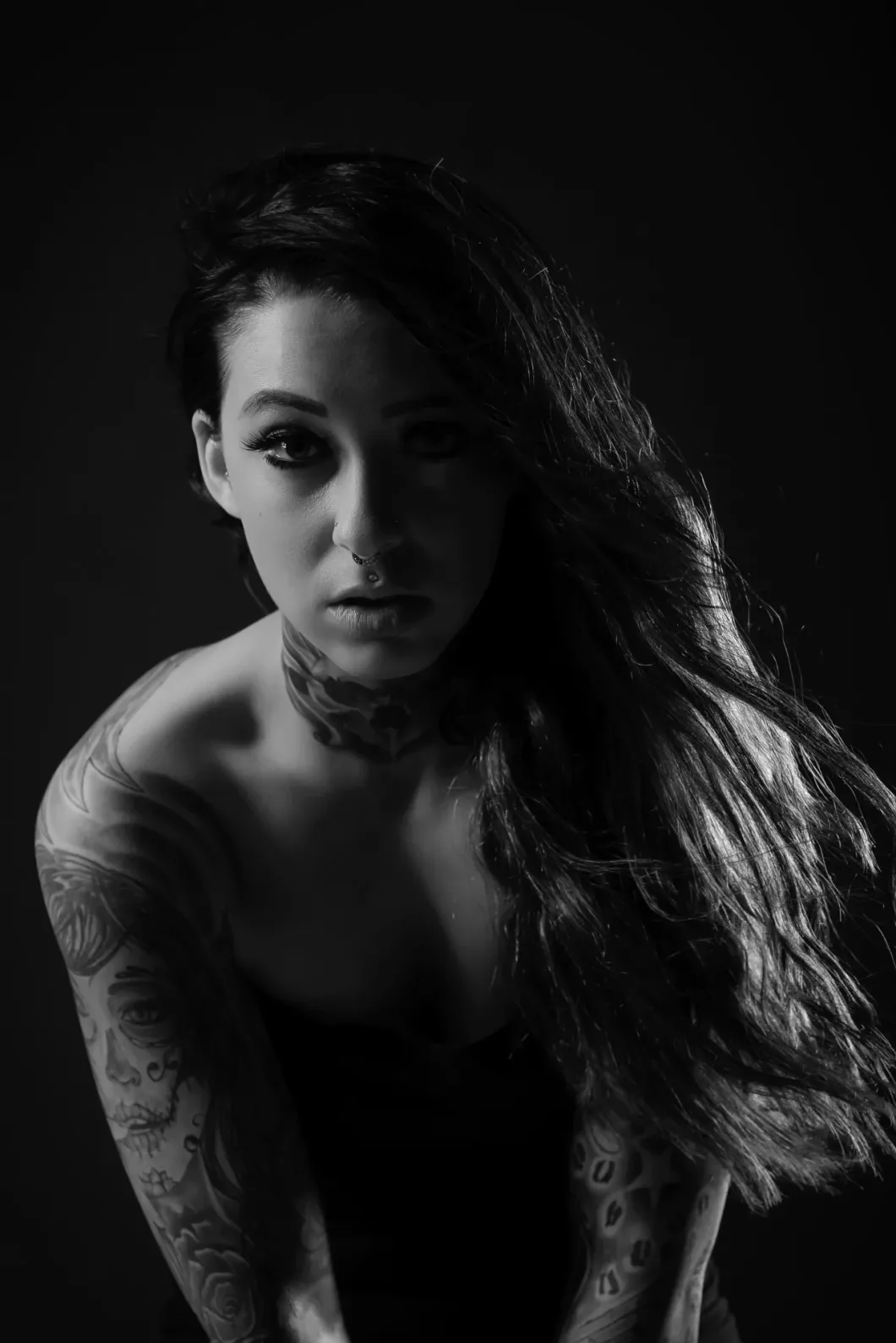 Frau mit Langhaarfrisur und Tattoos, dunkles Porträt, ausdrucksvolle Stimmung.