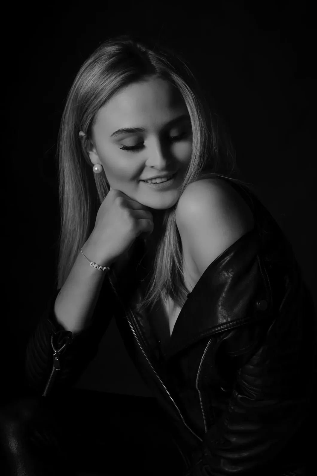 Frau in Lederjacke, zeigt Schulter, lächelt, Schwarz-Weiß-Porträt, sinnlich, elegante Pose.