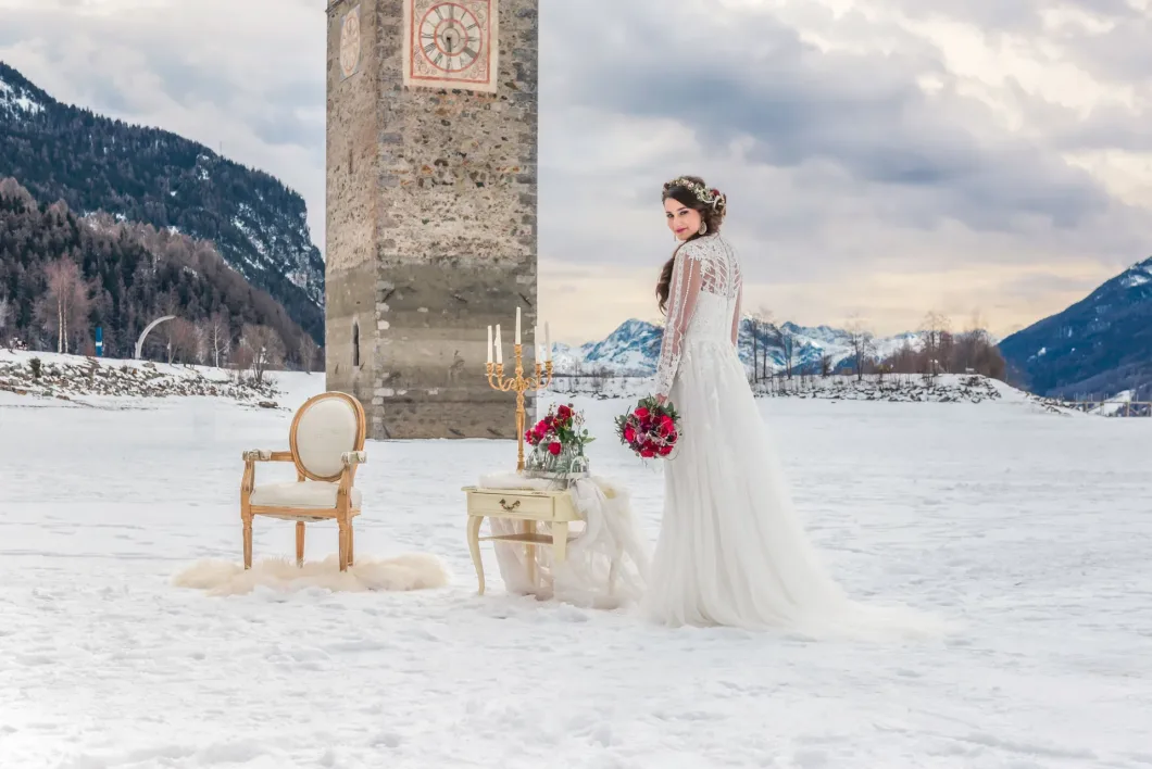Braut im Schnee vor mittelalterlichem Turm mit Blumen und Dekoration.