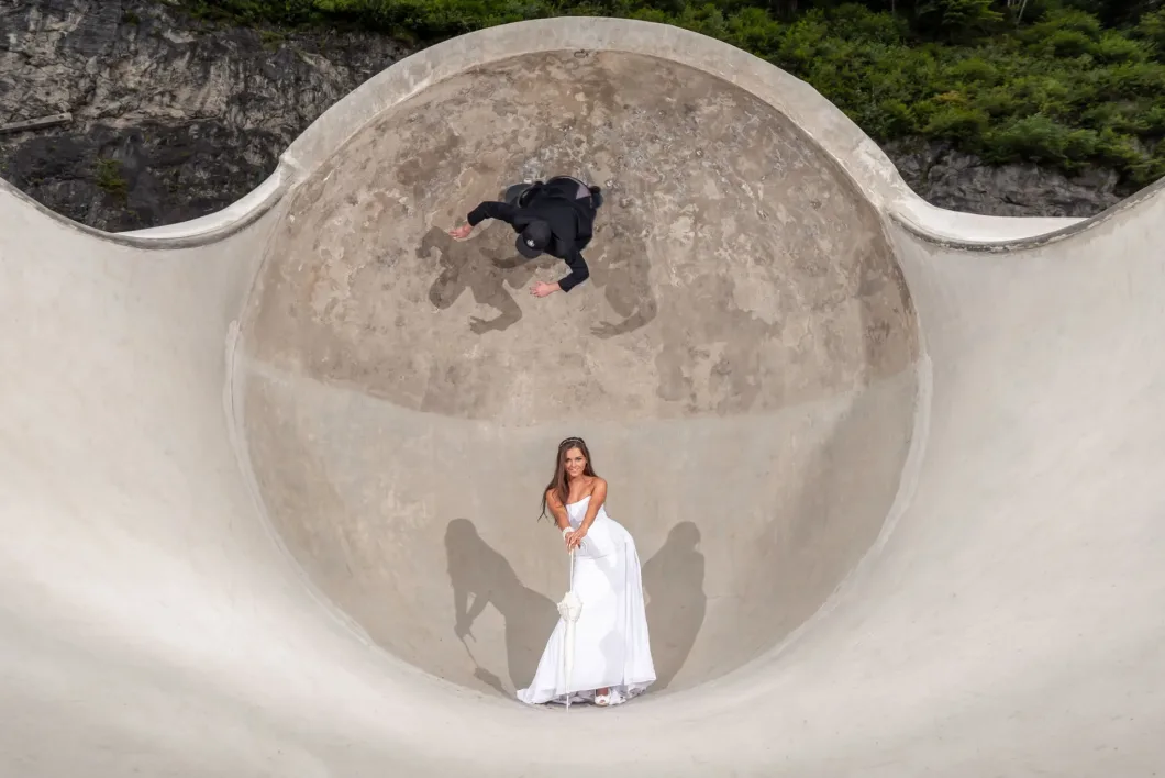 Braut im Brautkleid an Rampe, skatet ein Mann im schwarzen Anzug darüber hinweg.