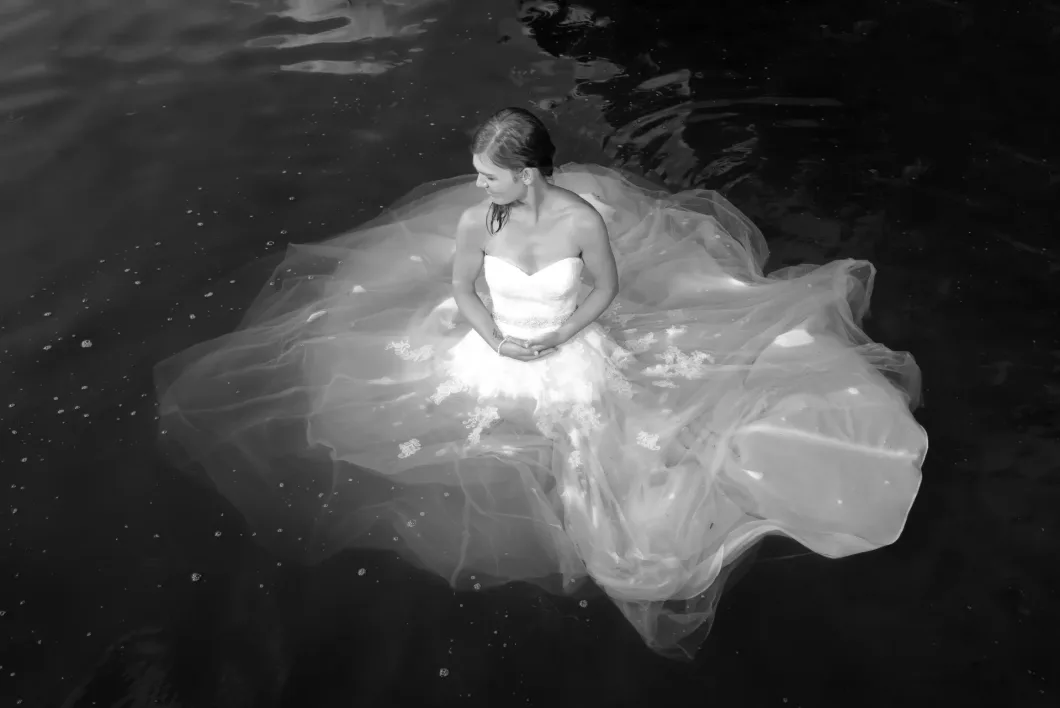 Braut im Wasser mit voluminösem Kleid, Schwarz-Weiß, kunstvolle Fotografie.