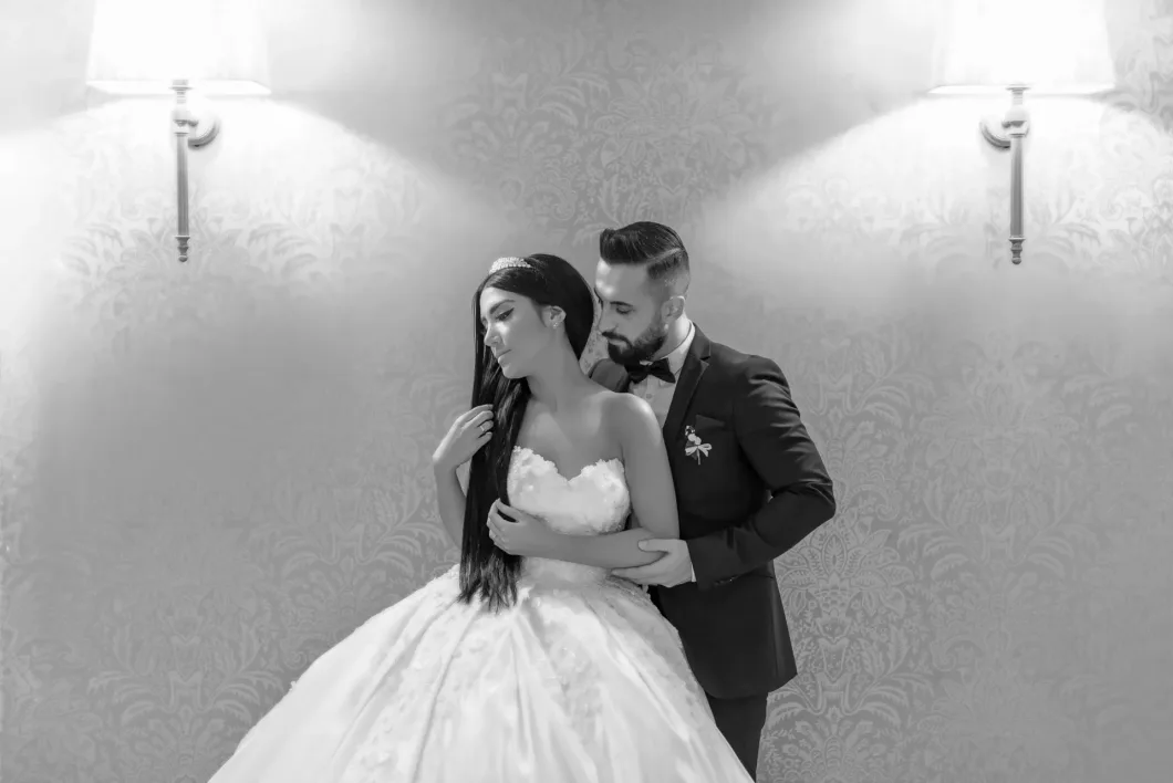 Brautpaar umarmt sich innig unter zwei Wandlampen, Hochzeit, schwarz-weiß.