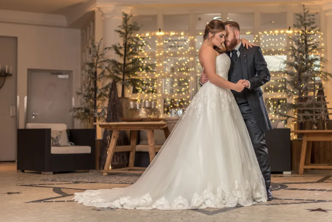 Brautpaar tanzt innig auf eleganter Hochzeit mit Lichterketten im Hintergrund.
